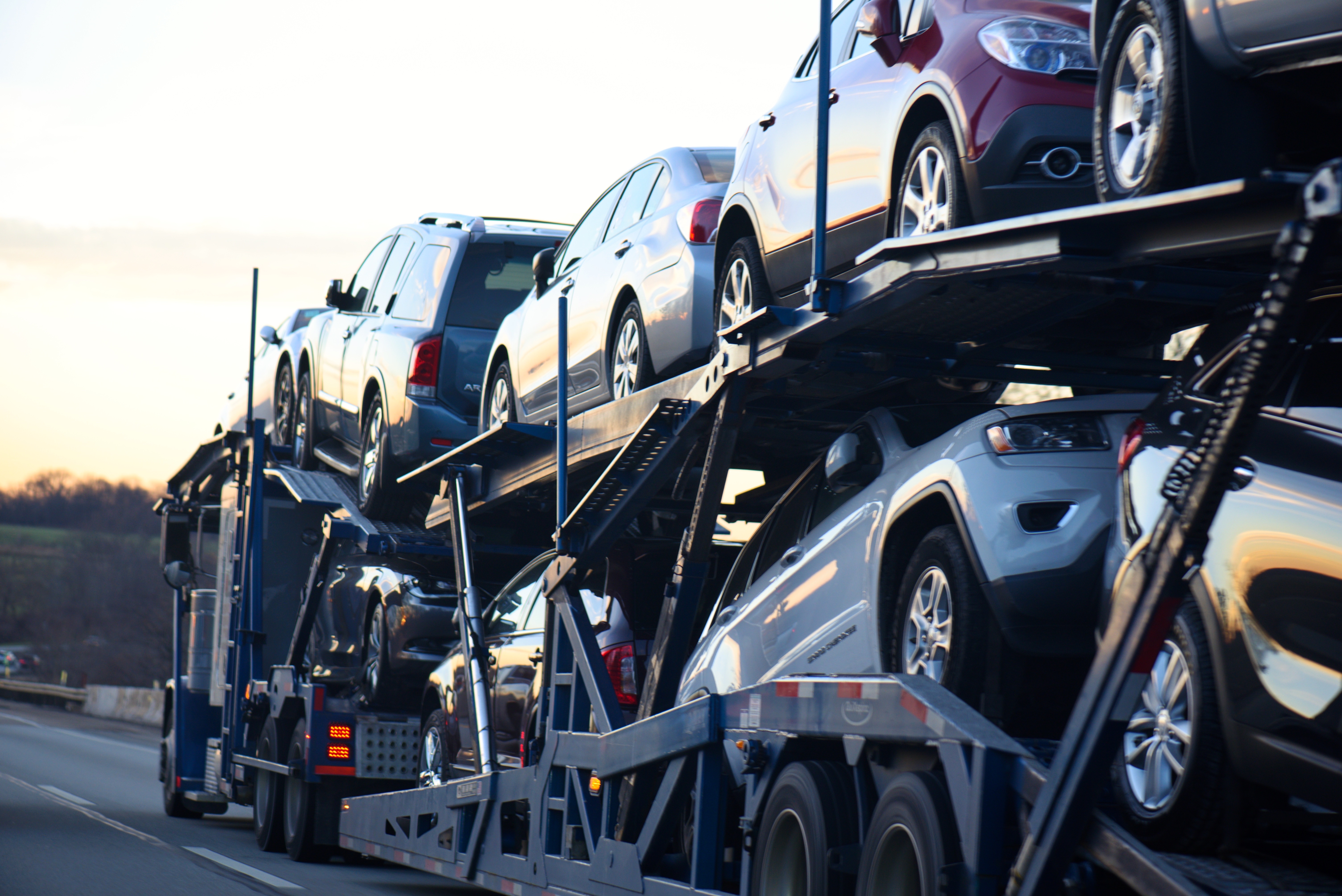Open auto transport carrier loaded with multiple vehicles on the highway